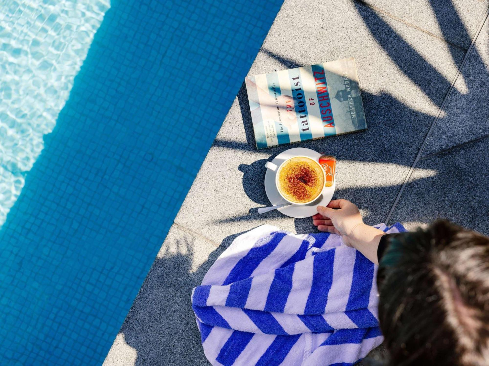 พูลแมน บริสเบน แอร์พอร์ต Hotel ภายนอก รูปภาพ A woman reading a book by the pool